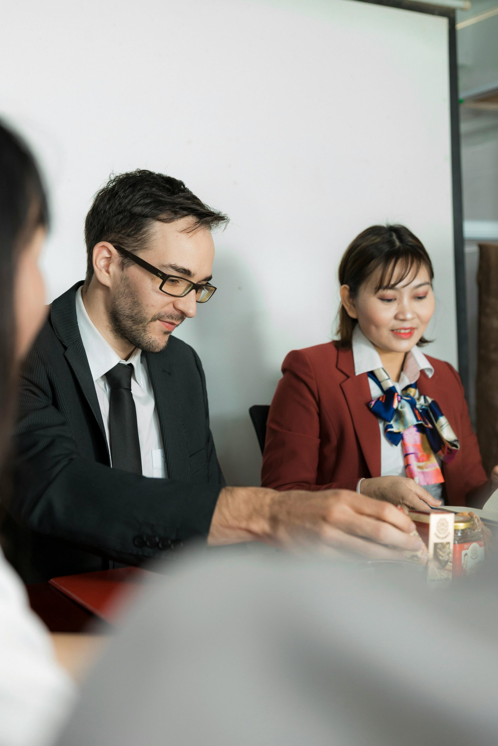 Two professionals engaged in a business meeting, seated at a conference table.